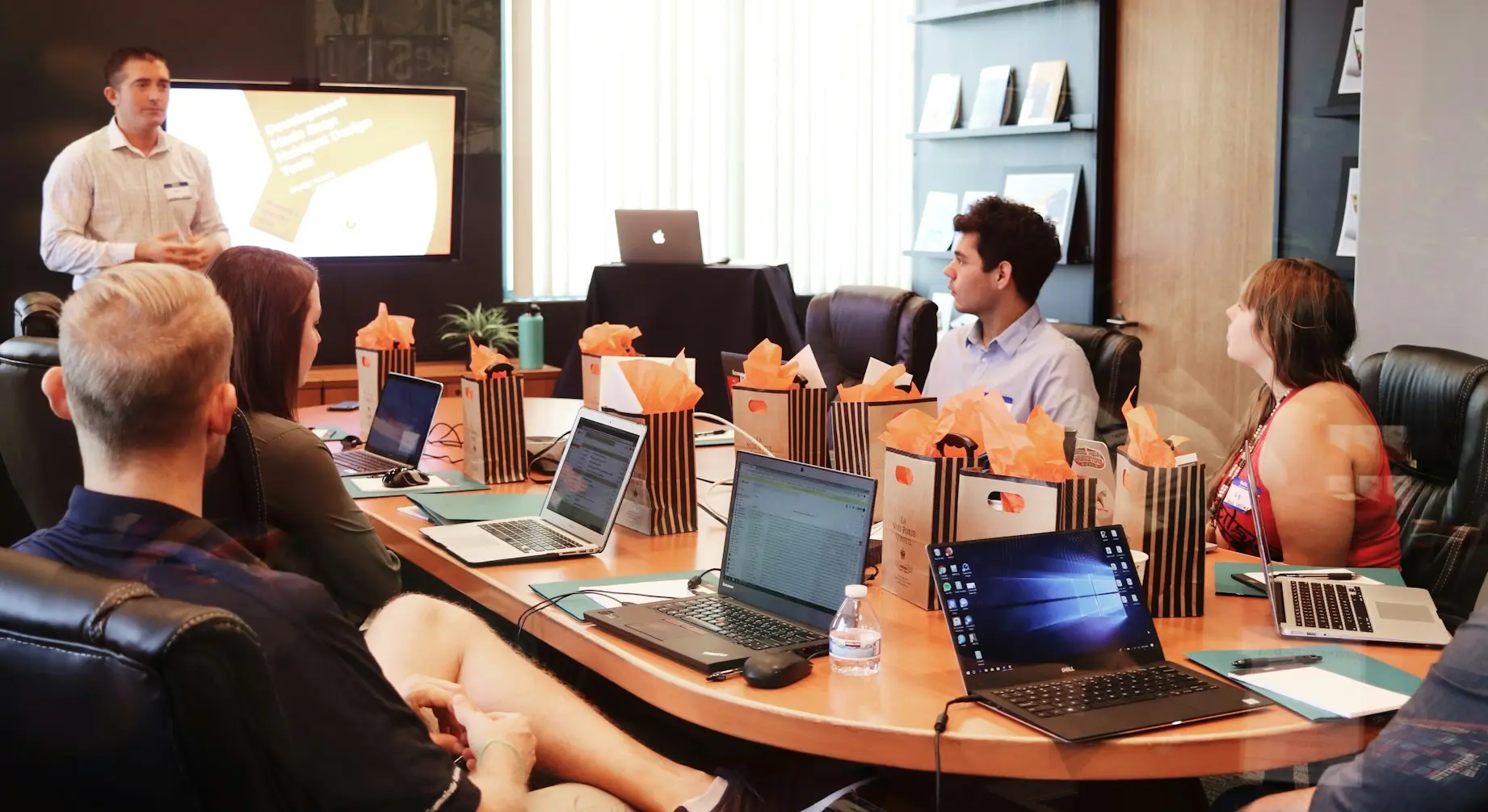man standing in front of people sitting beside table with laptop computers