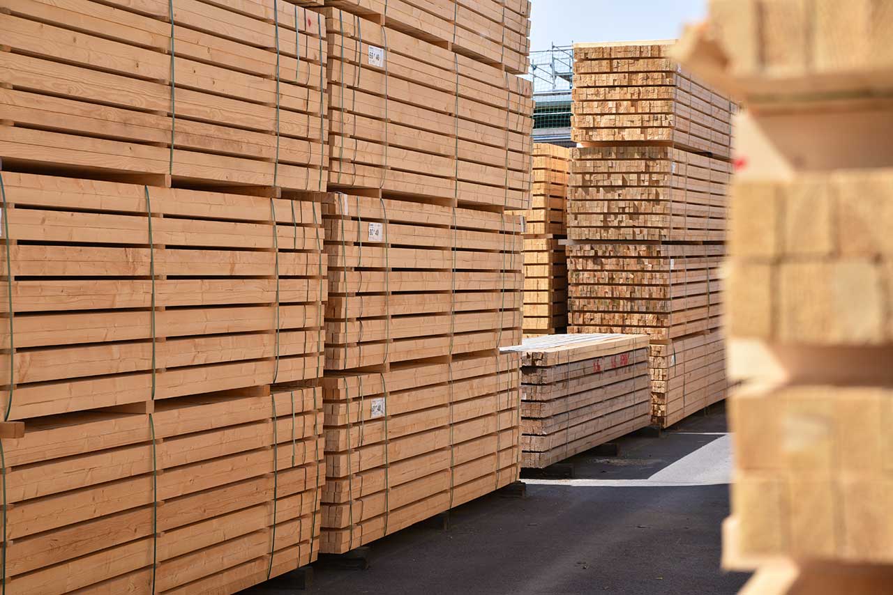 Stacks of neatly arranged lumber boards in a yard, ready for transportation or construction use.